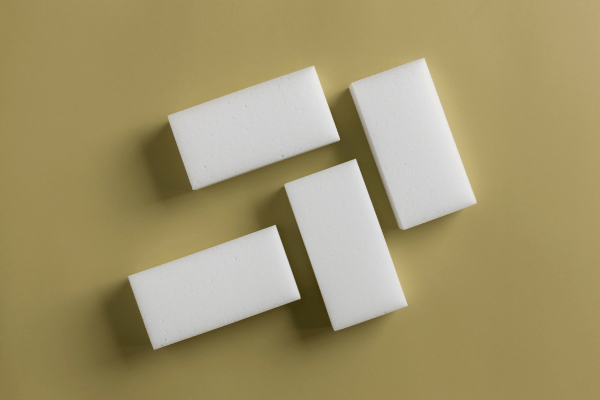 Four white magic erasers arranged neatly on a beige surface, ideal for effective cleaning tasks.