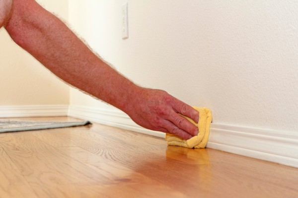 Cleaning baseboards with yellow cloth
