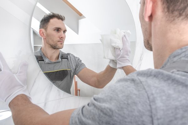 Person wiping a mirror with a white cloth.