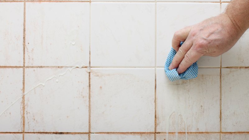 a person cleaning dirty shower tiles