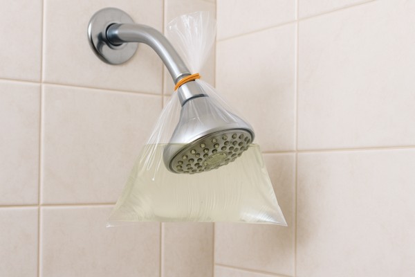 Showerhead soaking in vinegar-filled plastic bag for cleaning.